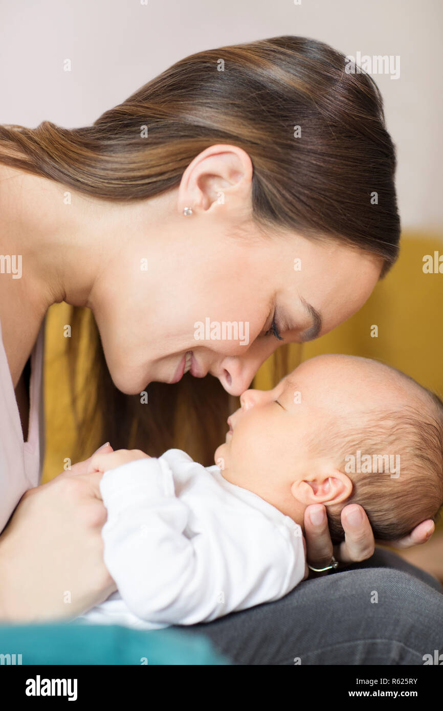 Liebevolle Mutter Kuscheln Baby Sohn und berühren Nasen Stockfoto
