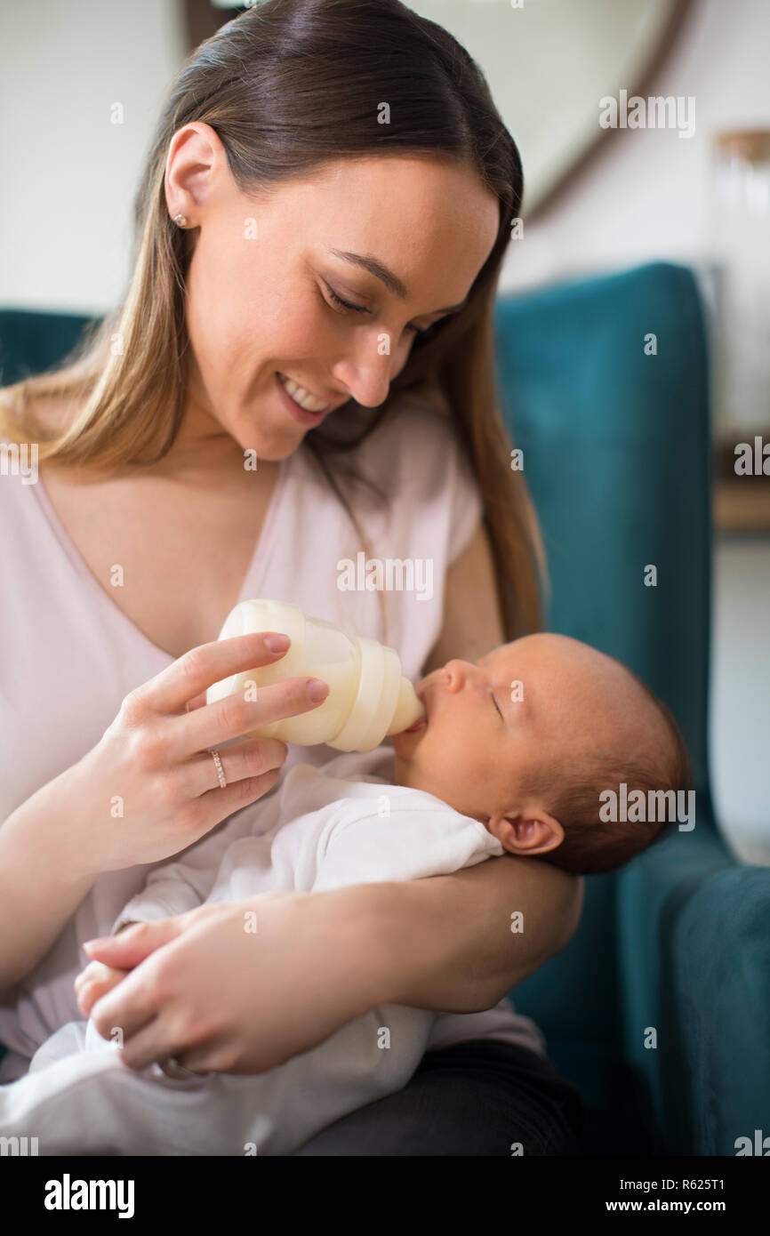 Liebevolle Mutter Fütterung neugeborenen Sohn mit Flasche zu Hause Stockfoto