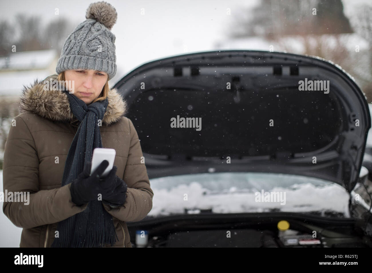 Weibliche Autofahrer Aufgeschlüsselt im Schnee für Pannenhilfe auf Handy Stockfoto