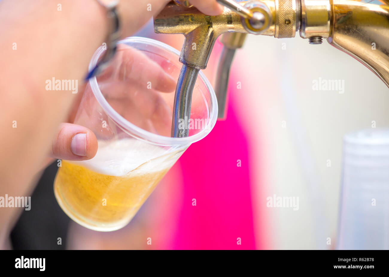 Ein Barkeeper Bier an einem Spender in Plastikbechern serviert Stockfoto
