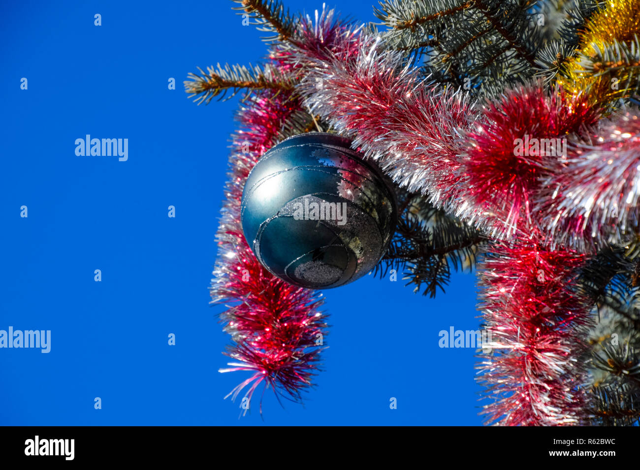 Neujahrsfeier Dekorationen. Kugeln, Lametta und Spielzeug und andere Dekorationen auf Weihnachten Baum steht unter freiem Himmel. Stockfoto