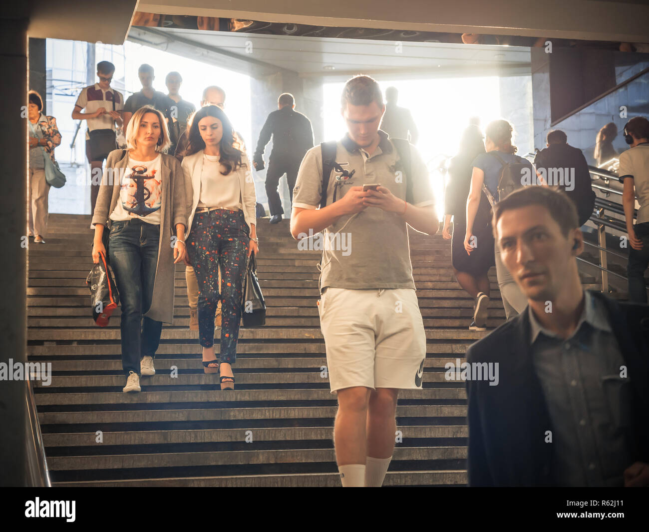 Moskau, Russland - September 6, 2018: Gewöhnliche Leute gehen, und gehen Sie auf die U-Bahn zur Hauptverkehrszeit. Menschen hinunter in die Unterführung. Silhouetten von Menschen zu Fuß auf der Treppe vor dem Hintergrund der Sonne. Stockfoto