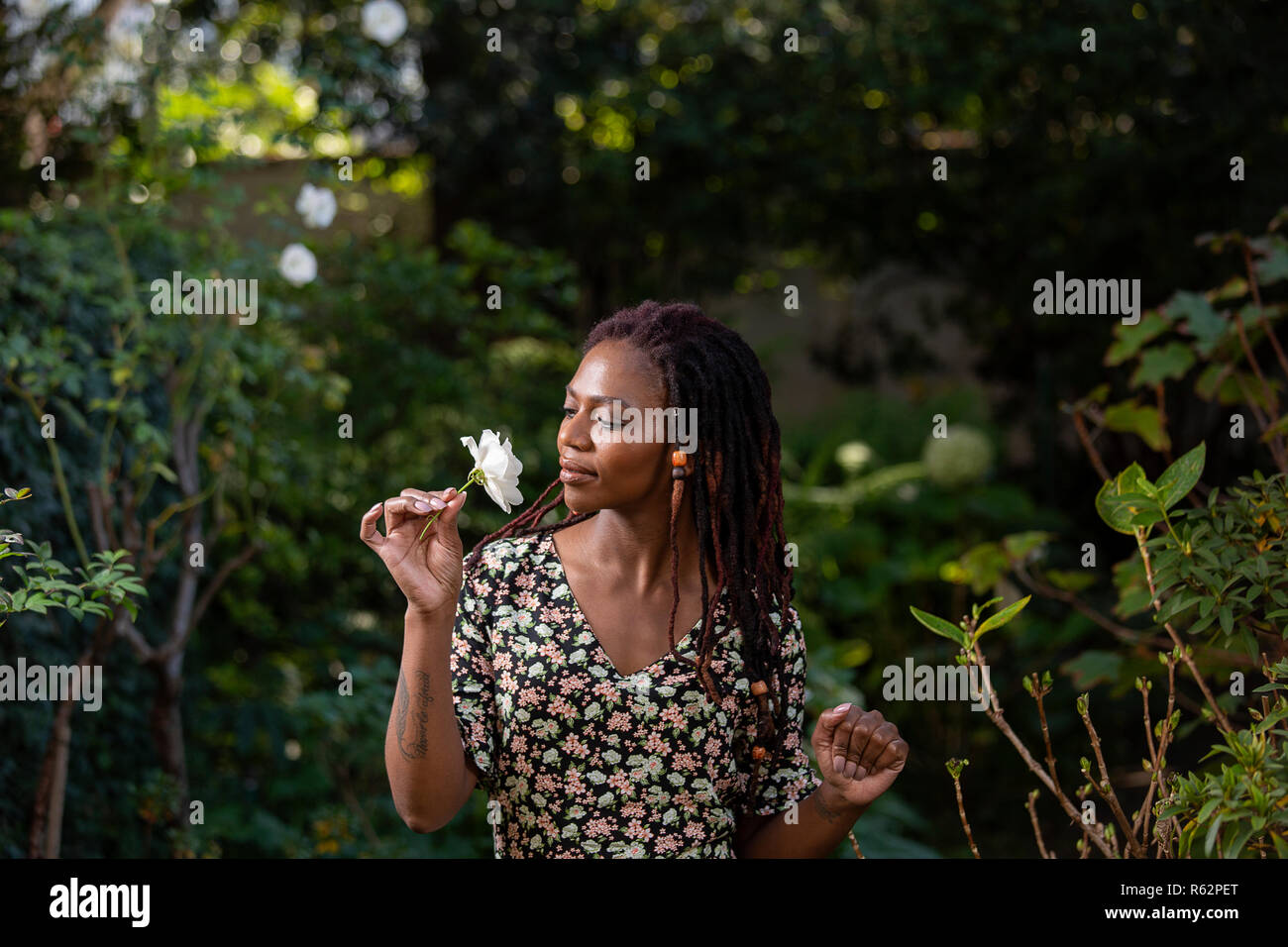 Eine afrikanische Frau riechen eine Rose in einem Garten Stockfoto