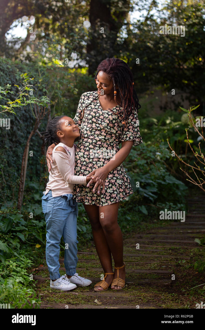 Mutter und Tochter an jedem anderen liebevoll auf einem Gartenweg Stockfoto