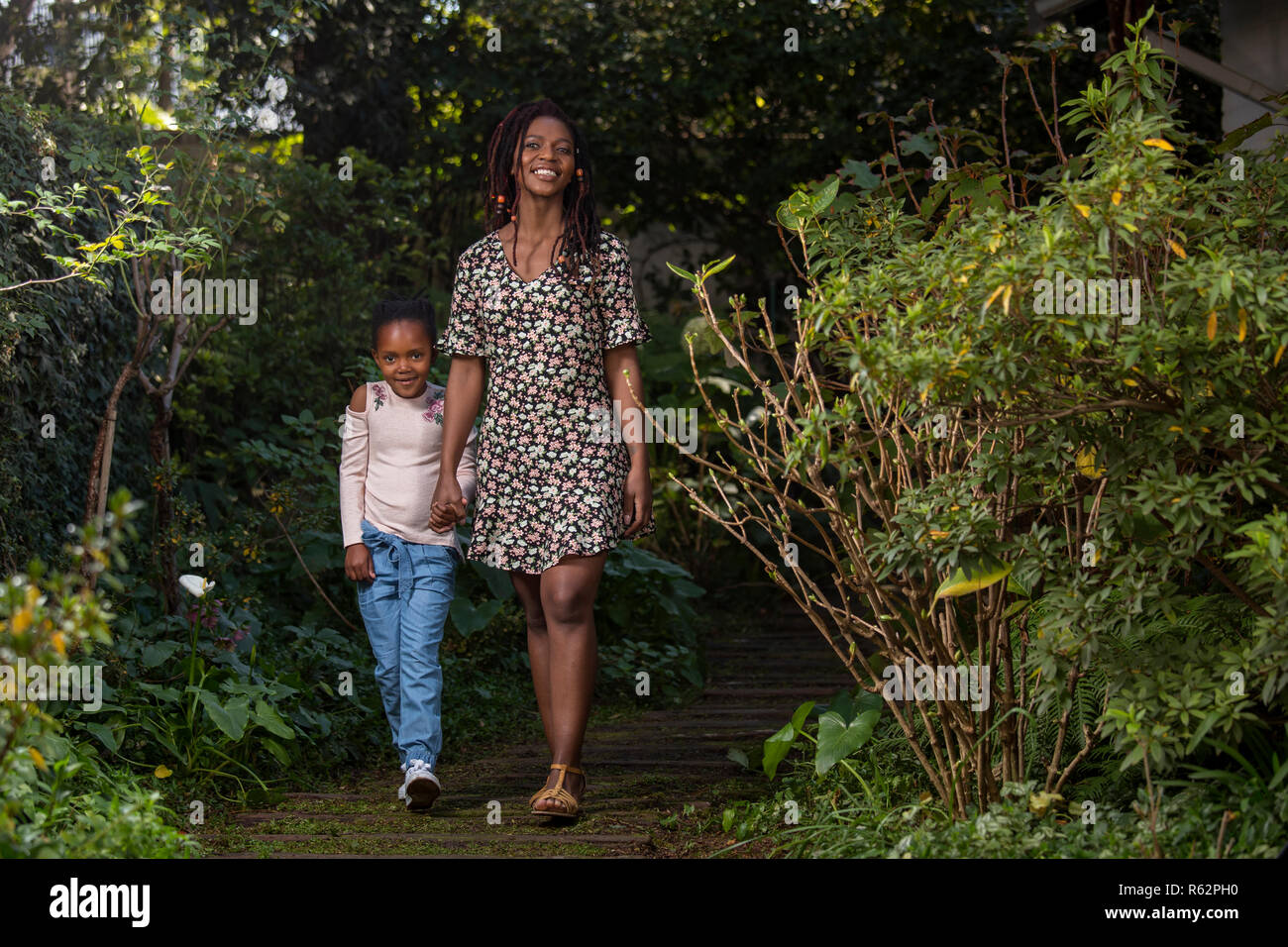 Mutter und Tochter halten sich an den Händen hinunter einen Garten Pfad Stockfoto