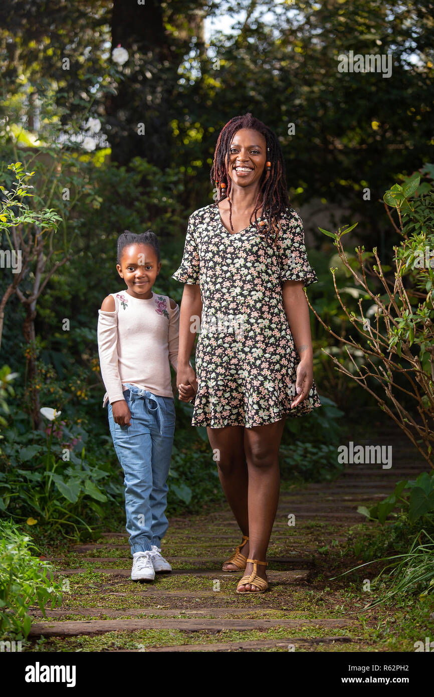 Mutter und Tochter halten sich an den Händen hinunter einen Garten Pfad Stockfoto