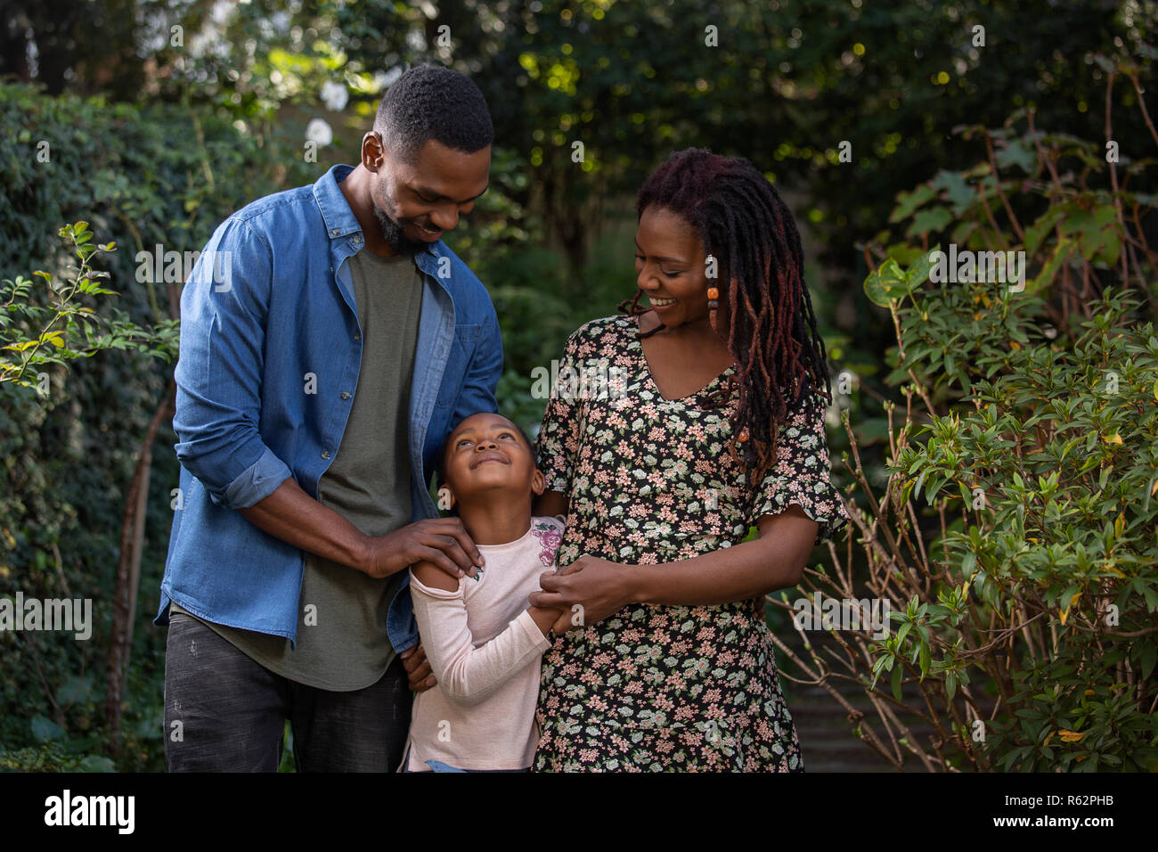 Eine Mutter, Vater und Tochter einander liebevoll Suchen in einem Park Stockfoto