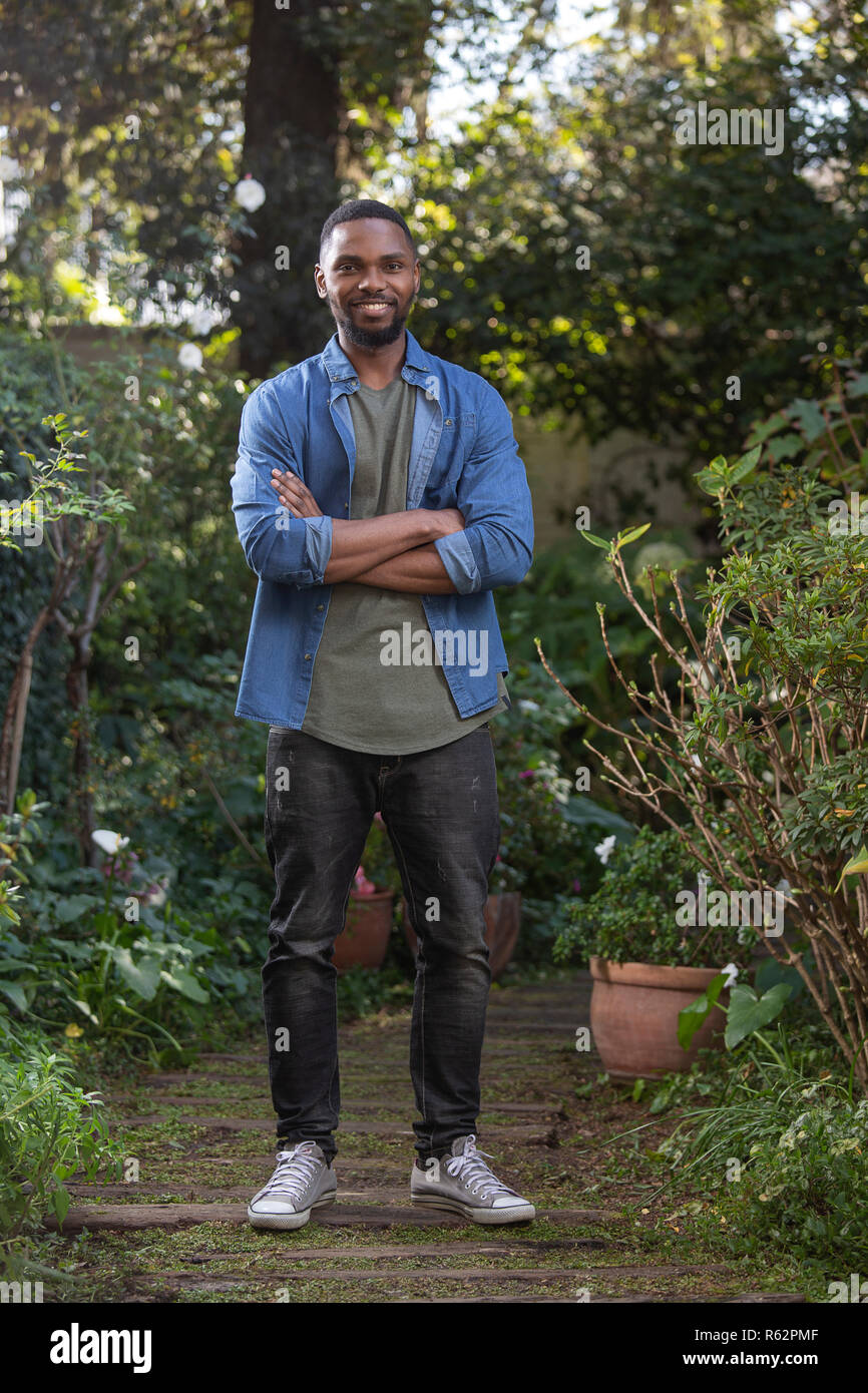 Ein afrikanischer Mann in einem Garten mit gekreuzten Armen Stockfoto