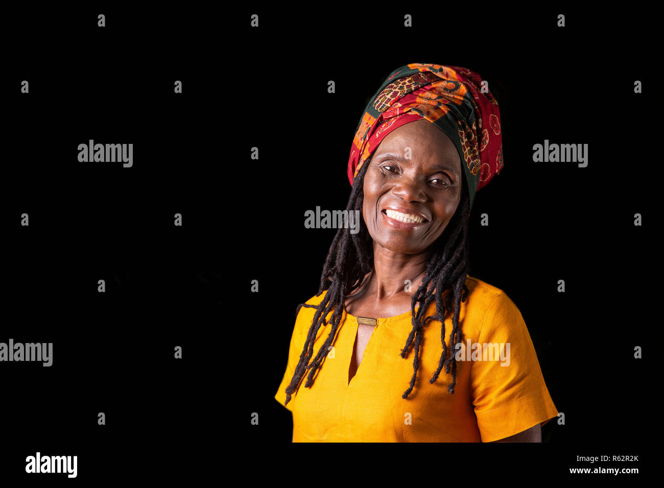 Eine ältere afrikanische Frau mit Kopftuch vor einem schwarzen Hintergrund Stockfoto Eine ältere afrikanische Frau mit Kopftuch vor einem schwarzen Hintergrund Stockfoto
