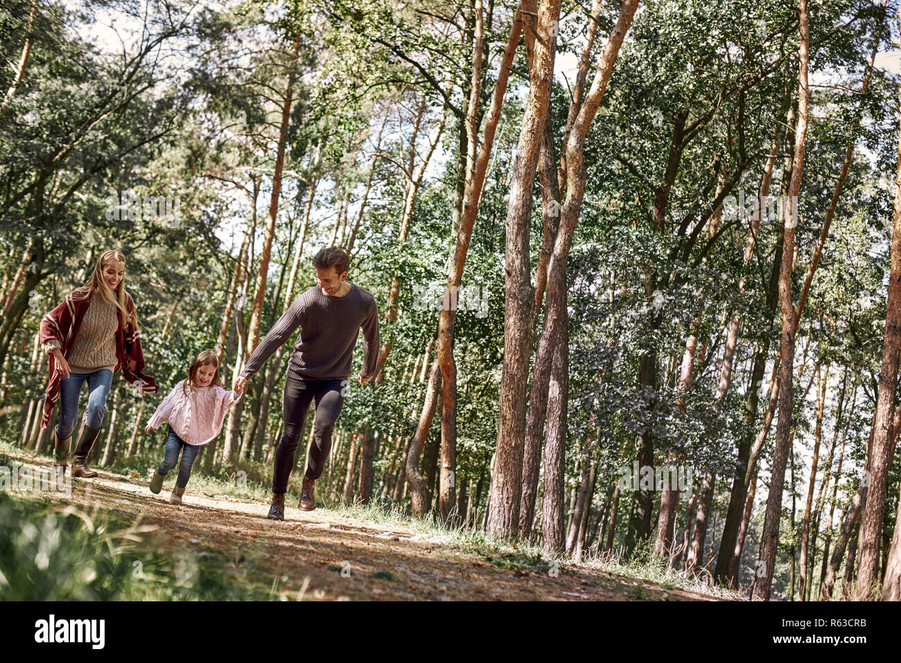 Glückliche Eltern mit ihrer Tochter halten Sie Hände und am Waldweg laufen Stockfoto