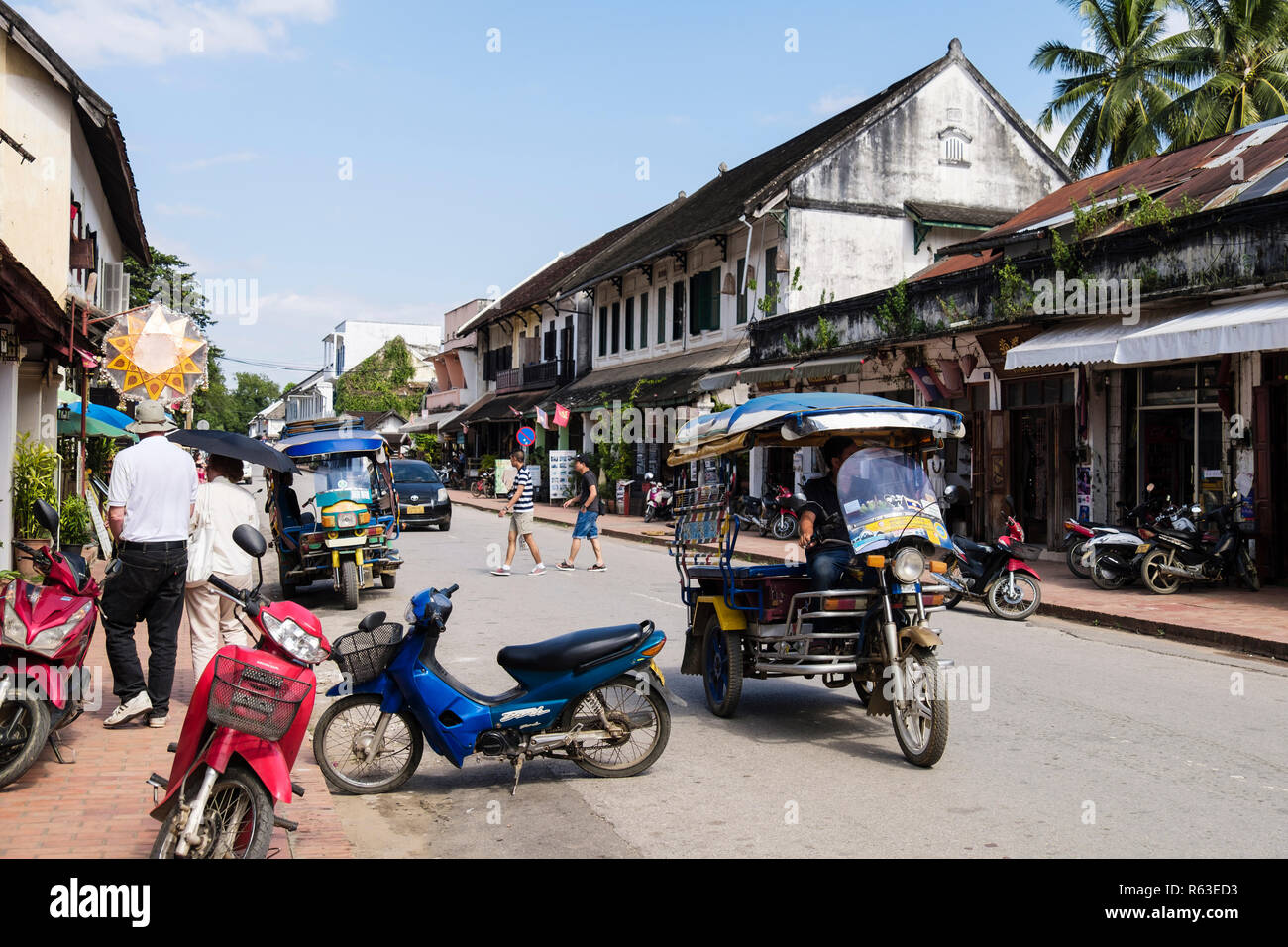 Typische Straßenszene mit Tuk Tuks und Geschäfte im kolonialen Stadtteil der alten Stadt. Sisavangvong Straße, Luang Prabang, Louangphabang Provinz, Laos, Asien Stockfoto