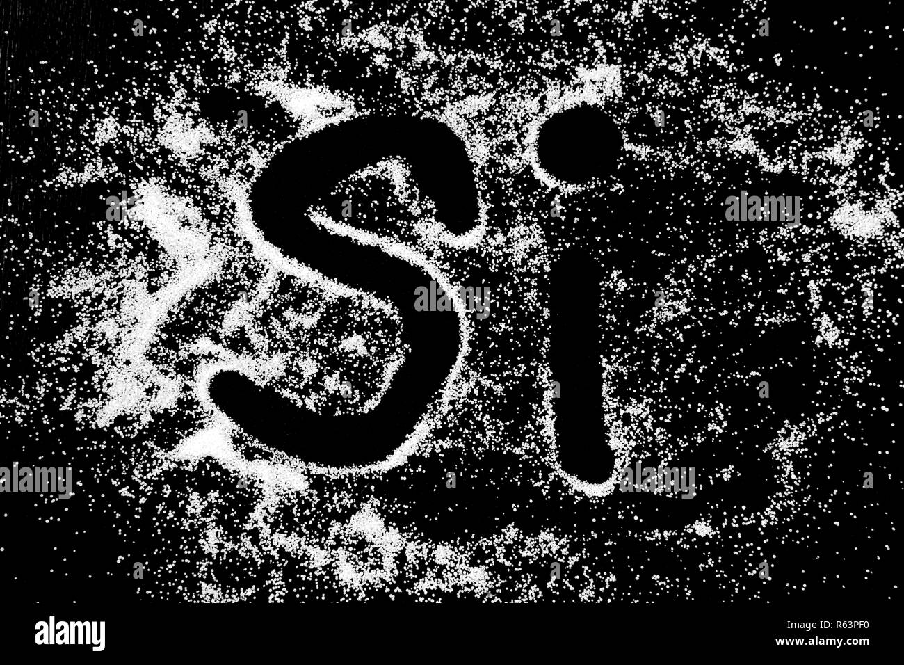 Ja Wort in Spanisch Sprache Si symbol Zeichnung mit dem Finger auf weißem Schnee Salz Pulver auf schwarzem Hintergrund. Großbuchstaben Stockfoto