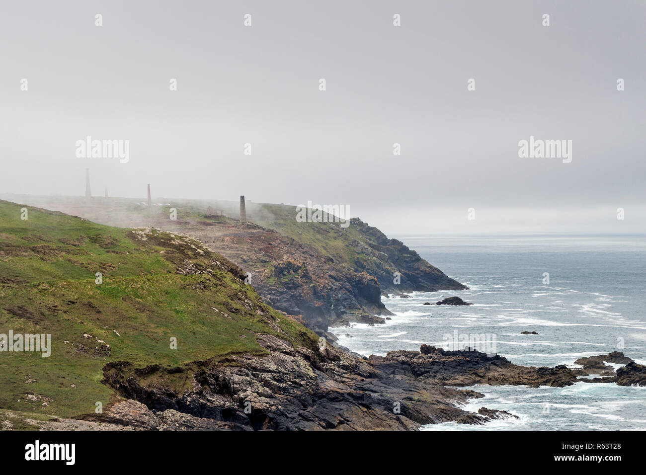 Nebel wirbeln um die Schornsteine und Halden des verlassenen Levant Minen, Botallack, St Just, Cornwall, Großbritannien Stockfoto