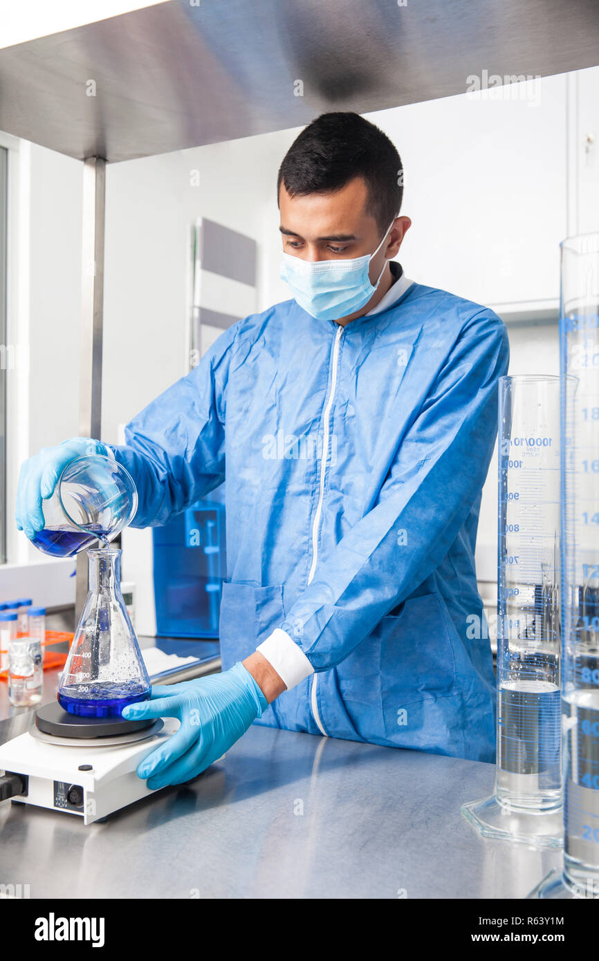 Junge männliche Wissenschaftler arbeiten mit einem Rührwerk im Labor in Blau gekleidet Stockfoto