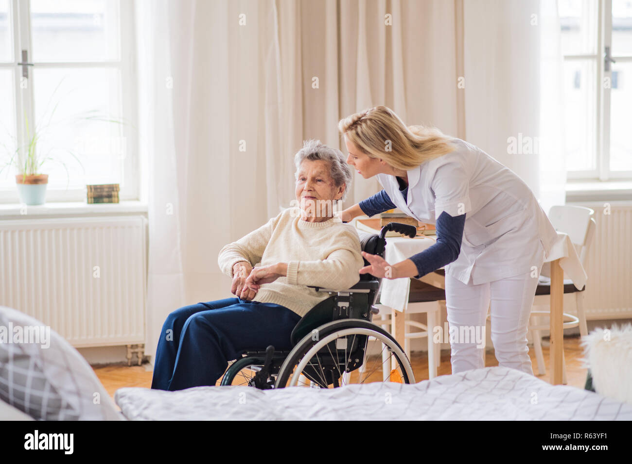 Eine Gesundheit Besucher an eine ältere Frau im Rollstuhl zu Hause sprechen. Stockfoto