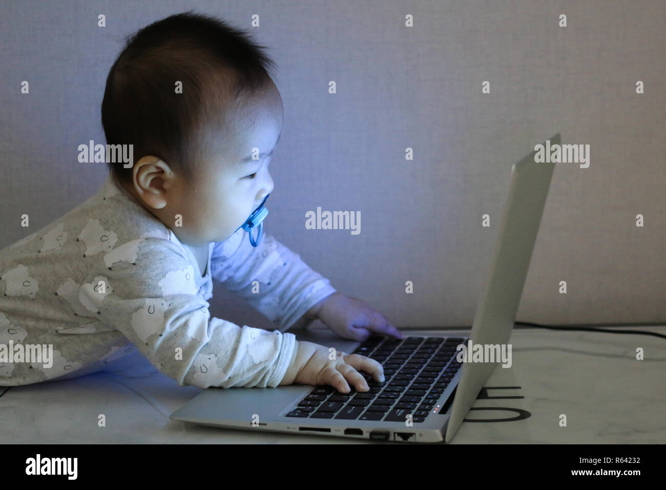 Asiatische baby arbeitet mit Laptop in der Dunkelheit Stockfoto