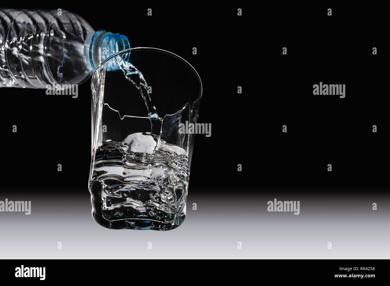 Ansicht von unten auf das Trinkwasser aus der Flasche in das Glas gegossen wird, Stockfoto