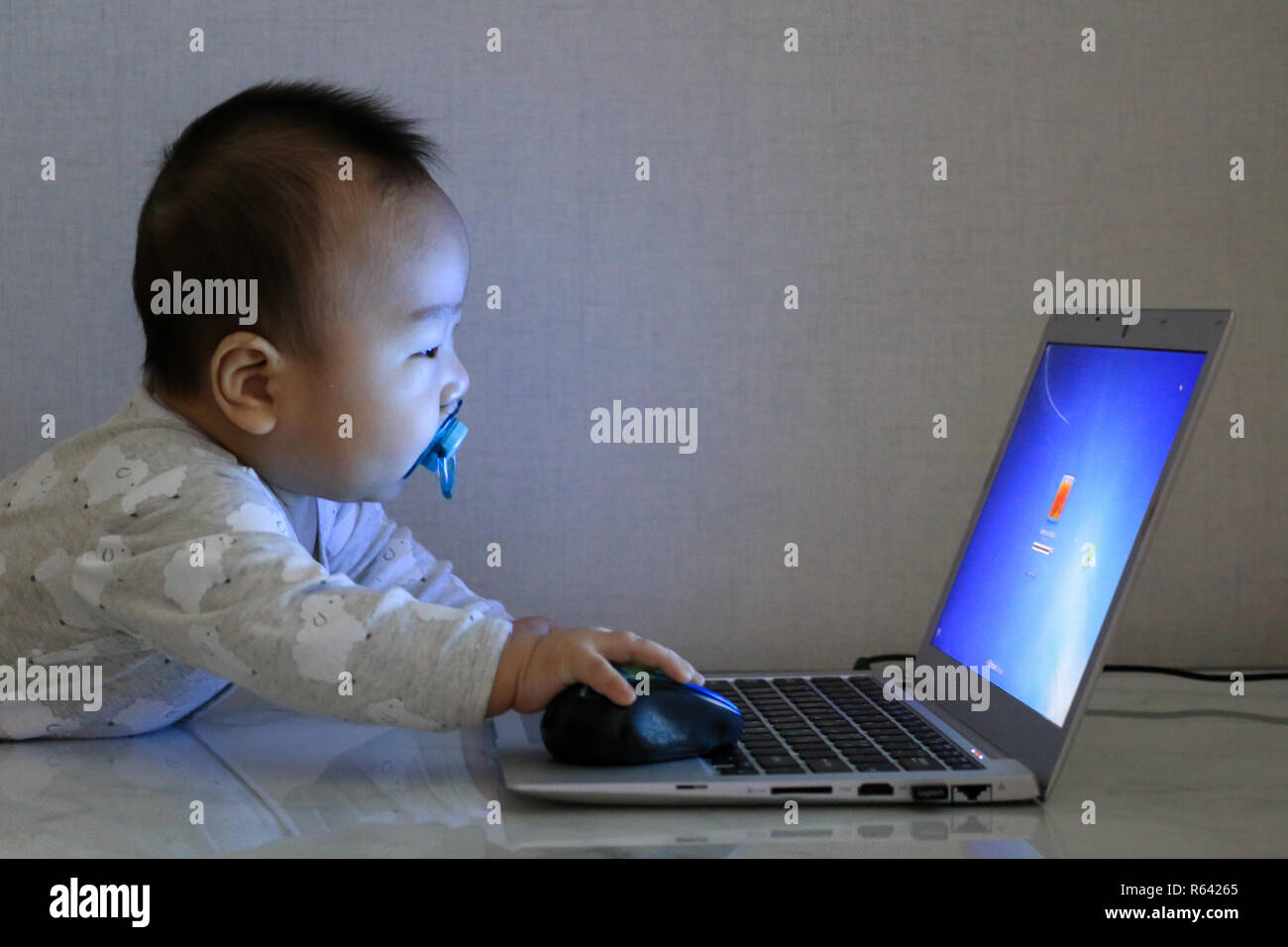 Asiatische baby arbeitet mit Laptop in der Dunkelheit Stockfoto