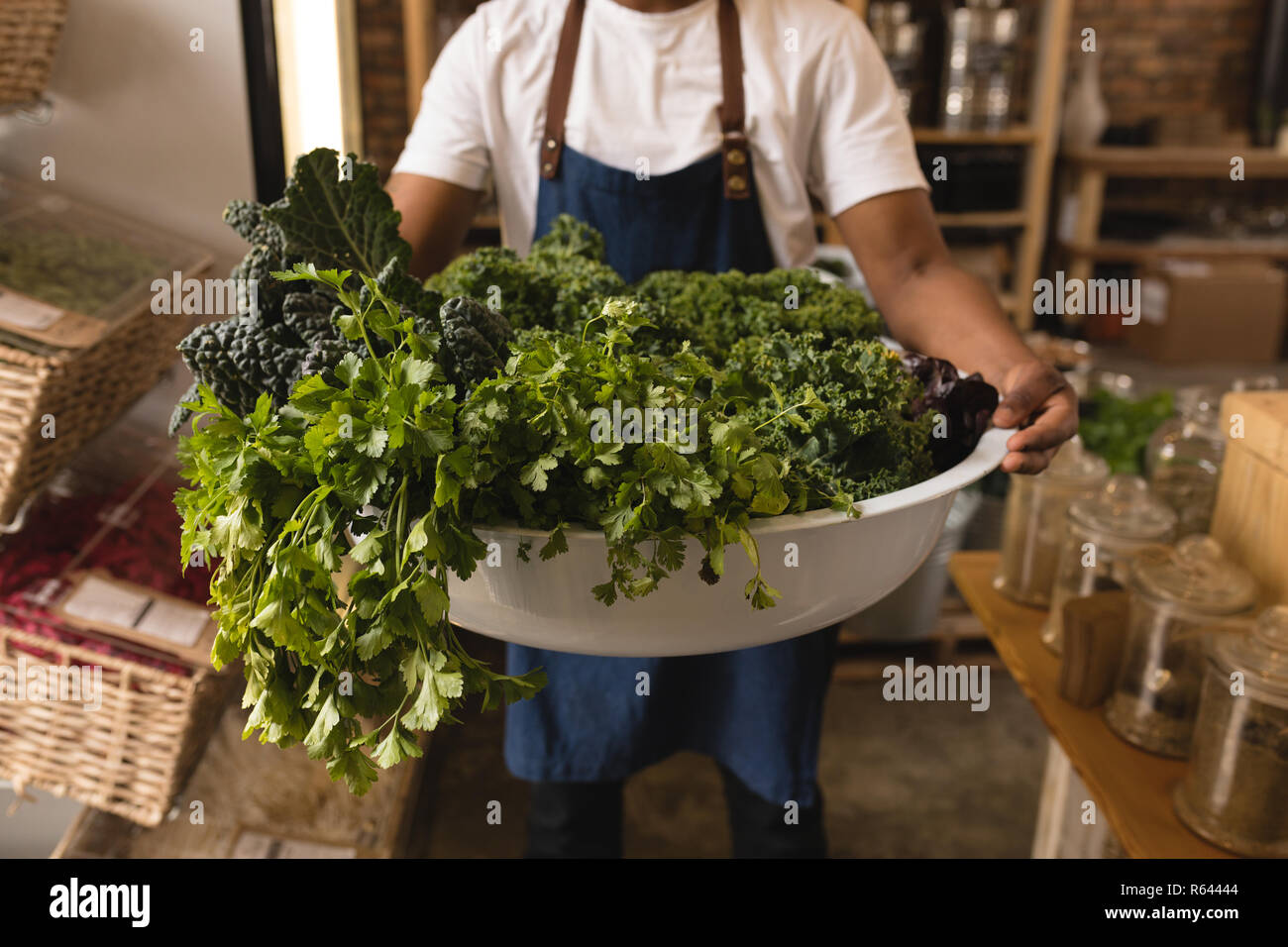 Männliche Bedienstete, die Wanne von grünem Gemüse im Supermarkt Stockfoto