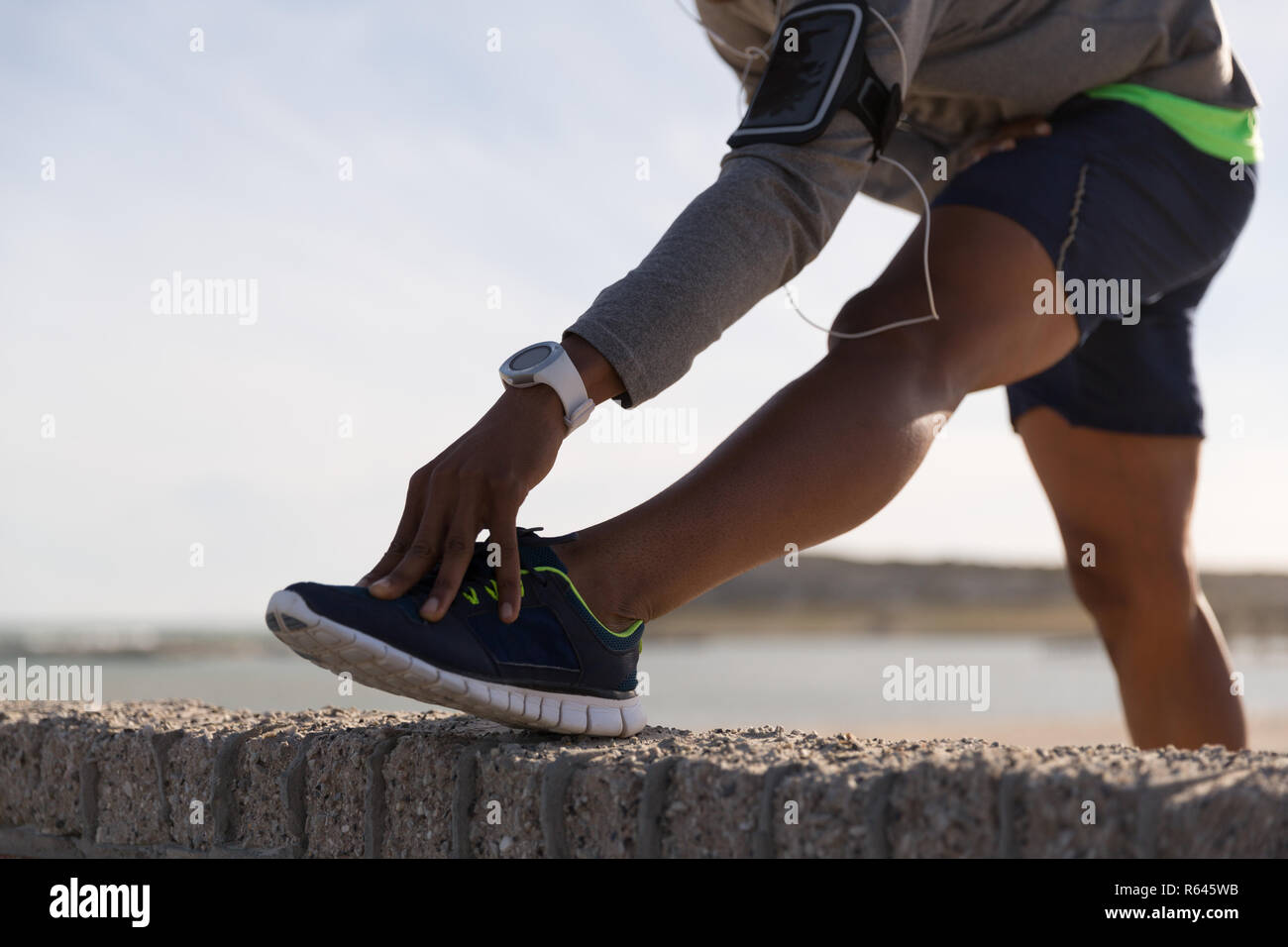 Männliche Athlet stretching auf umgebende Mauer Stockfoto