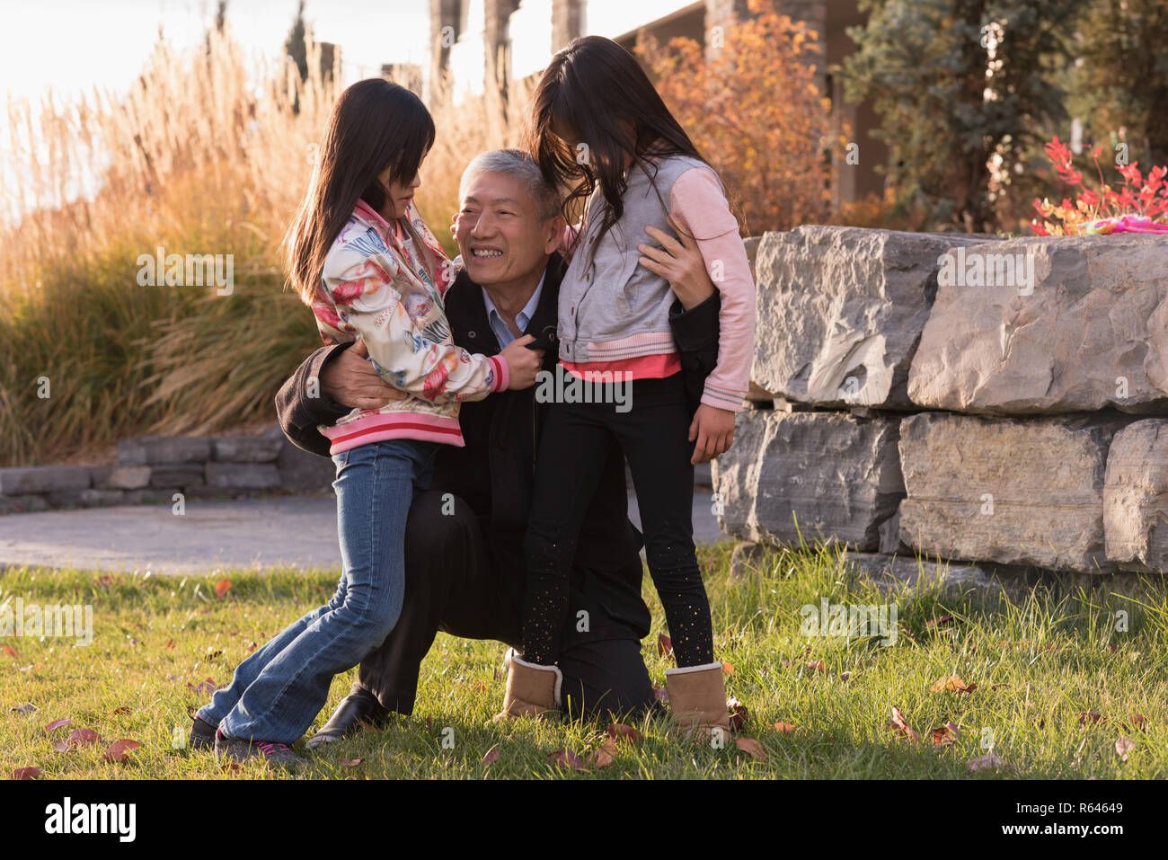 Großvater umarmt seine Enkelinnen an einem sonnigen Tag Stockfoto