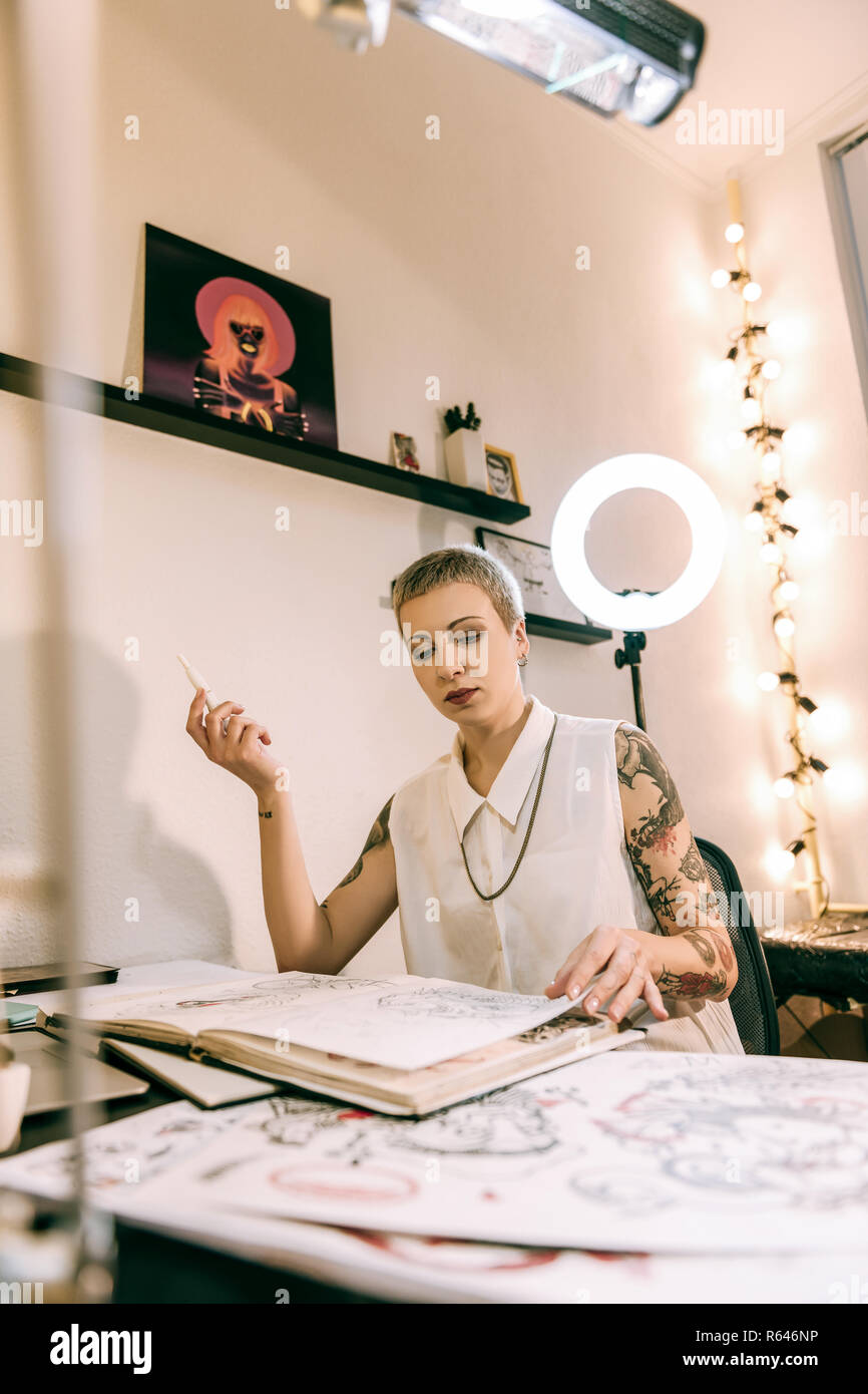 Kurzhaarige Frauen tattoo Master sitzen in Ihrem Büro Ecke und Rauchen Stockfoto
