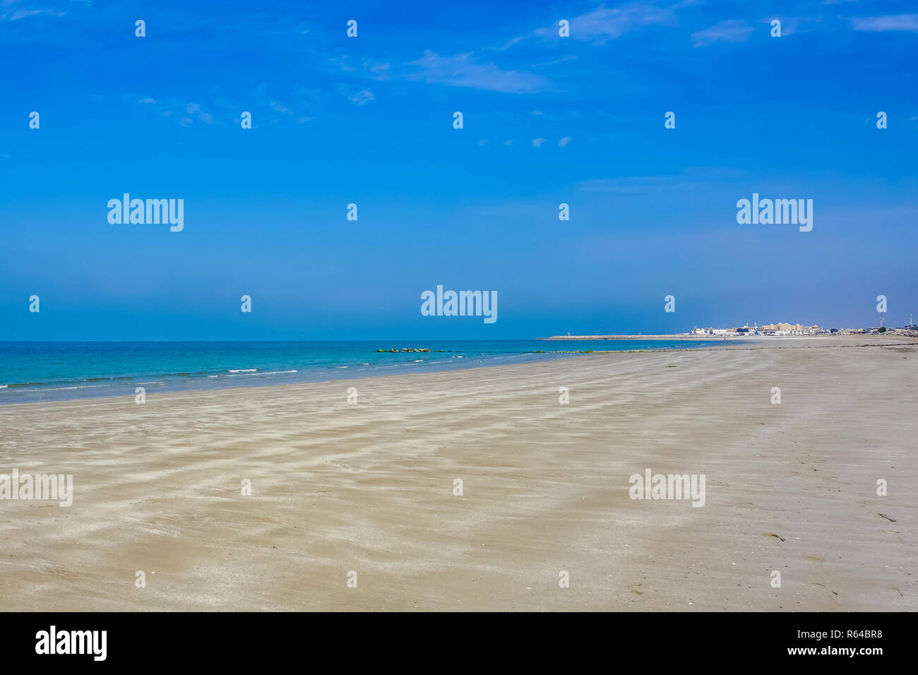 Ras Al Kaimah Sandstrand mit malerischen blauen Himmel Horizont und das Dorf im Hintergrund Stockfoto