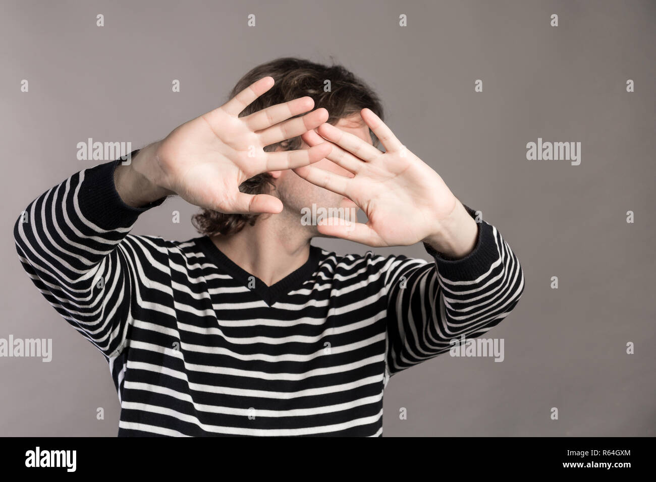 Ich gebe auf. Attraktiv unrasiert stilvollen Mann Palmen zeigt, demonstriert seine Unschuld, Rückkäufe, über grauer Hintergrund isoliert. Hübscher junger Mann Rai Stockfoto