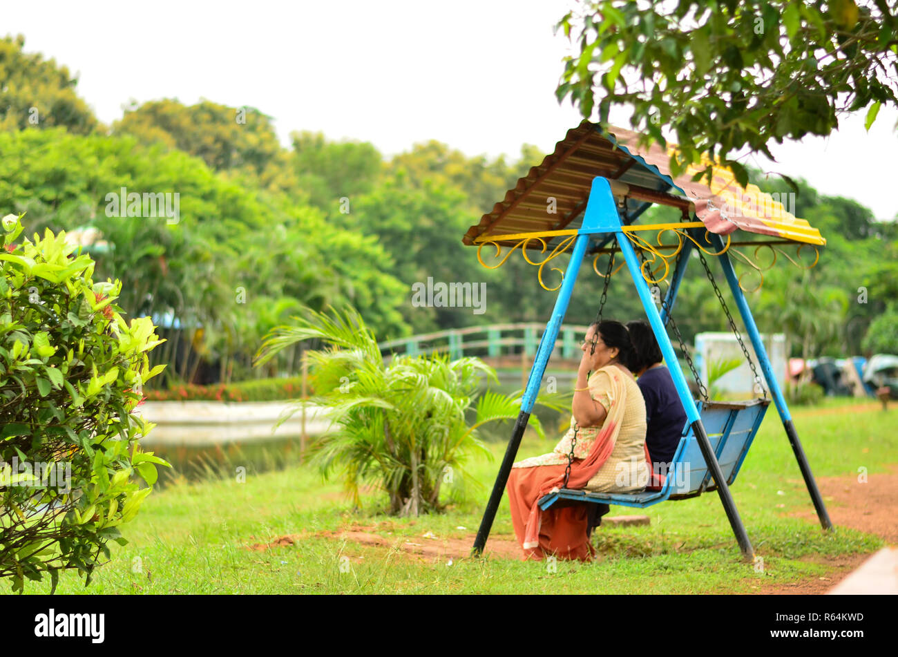 Natürliche ehrliche Side Shot eines älteren Dame und junge Frau (nicht sichtbar) auf einer Schaukel sitzend in einem Park Stockfoto