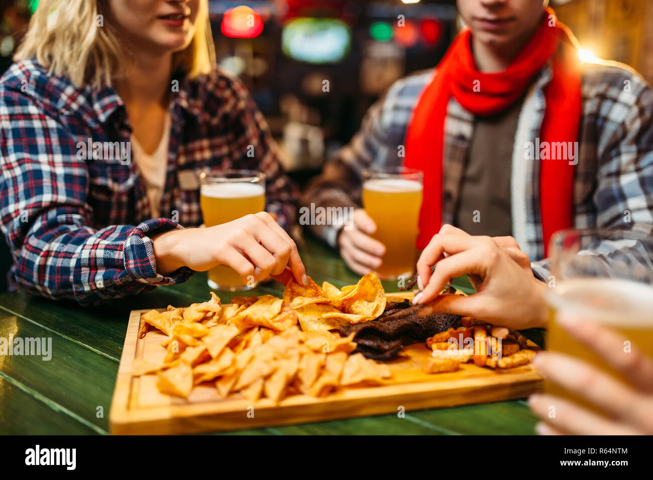 Fußball-Fans trinkt Bier und isst Chips am Tisch in der Sports Bar. Sieg feiern, die TV-Ausstrahlung, junge Freunde Freizeiten im Pub Stockfoto