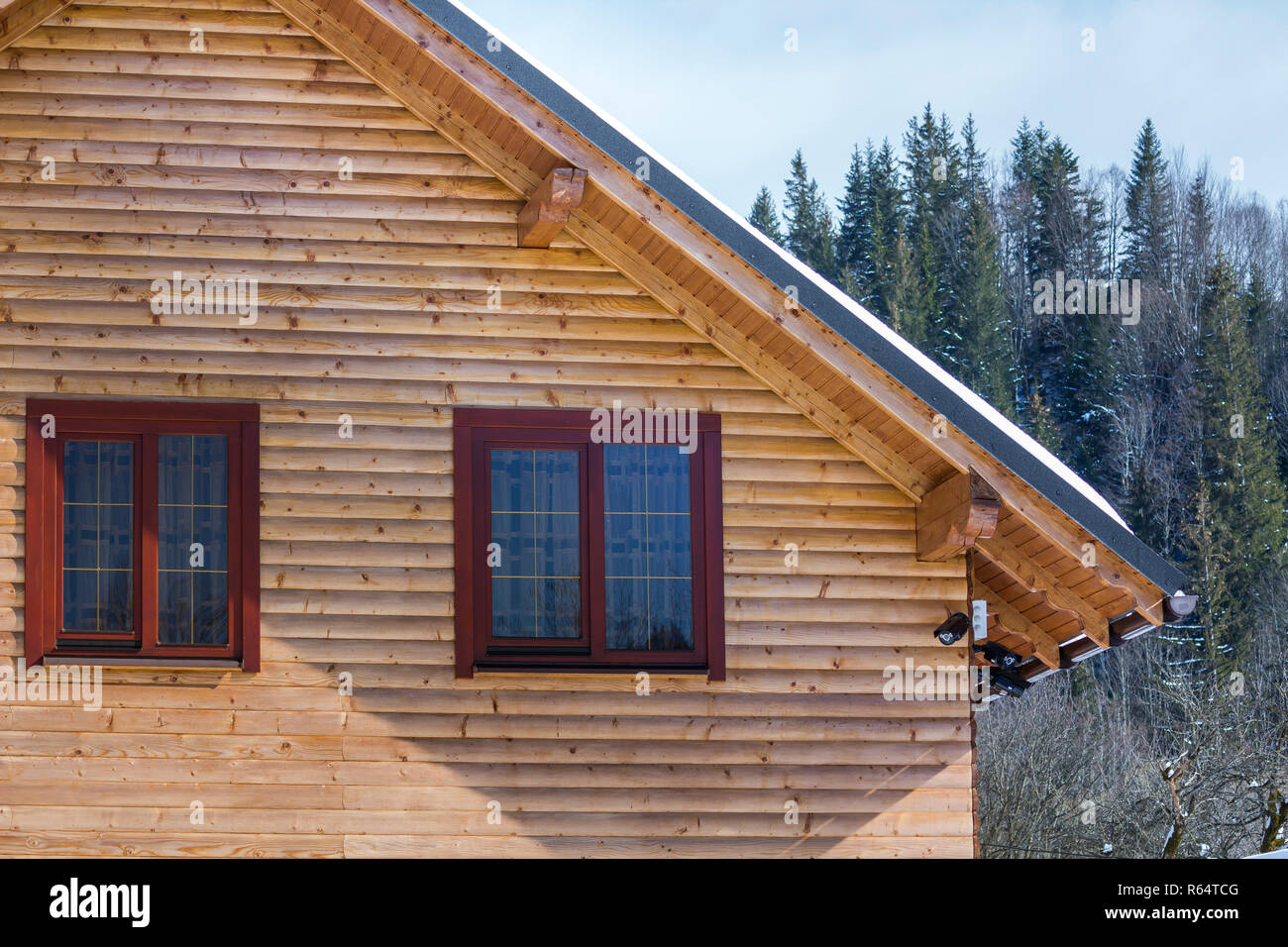Detail oben auf Holz- ökologische traditionelle Ferienhaus aus Holz Materialien mit steilen Dach, Zimmer im Dachgeschoss mit Schnee auf sonnigen Wintertag abgedeckt. Alte tradit Stockfoto
