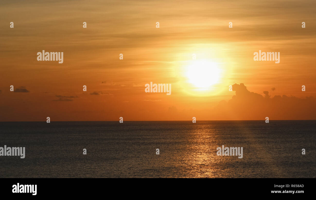 Orange Sonnenuntergang mit riesigen Sonne und einigen Wolken in Bali. Stockfoto