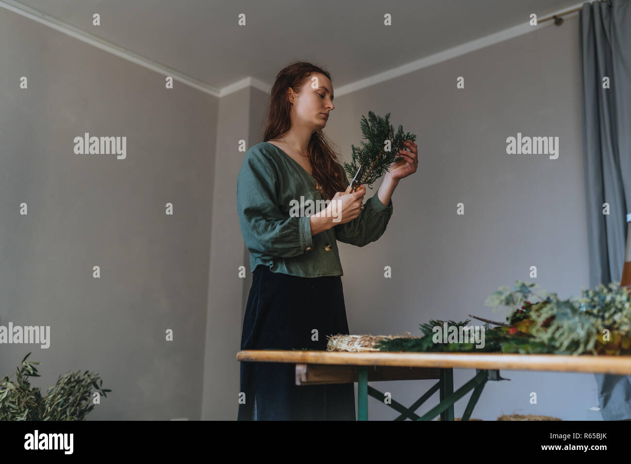 Foto der jungen kaukasischen Blumenhändler, die Schneiden ist eine Tanne Verzweigung vor ein Client in Ihrem eigenen Blumenladen Stockfoto