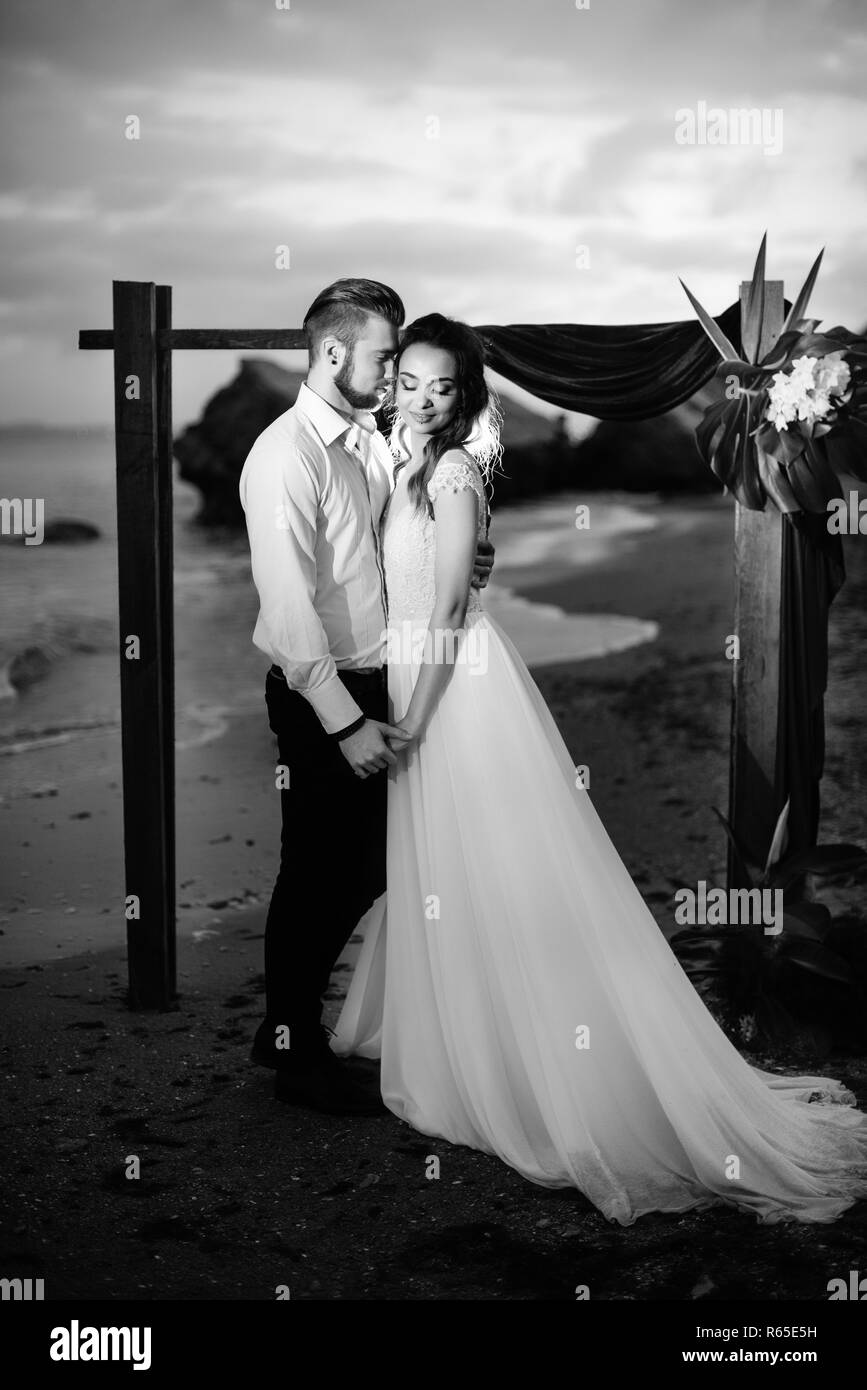 Junges Paar Bräutigam und Braut mit einem Blumenstrauß am Abend am Strand Stockfoto