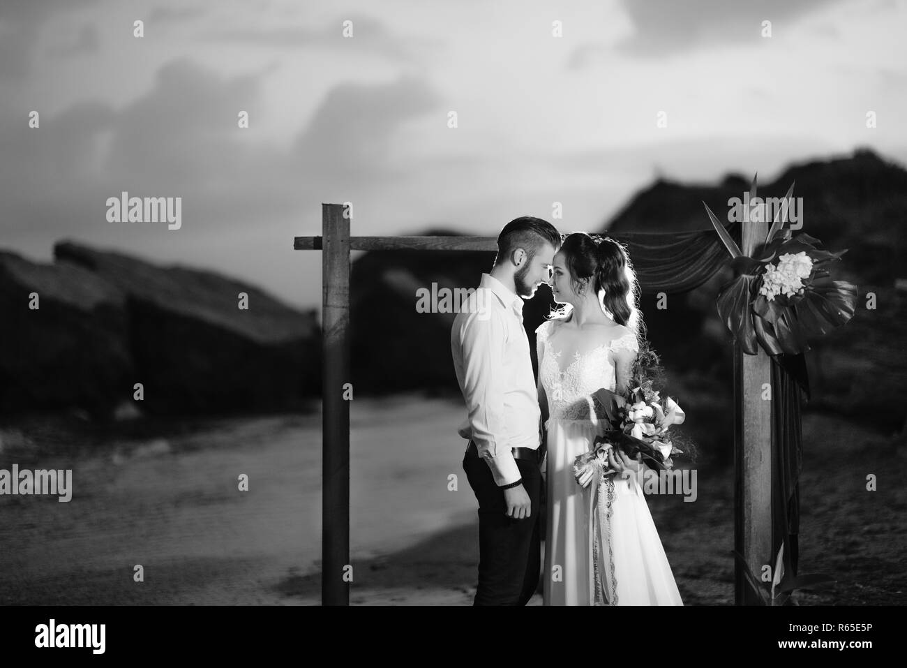 Junges Paar Bräutigam und Braut mit einem Blumenstrauß am Abend am Strand Stockfoto