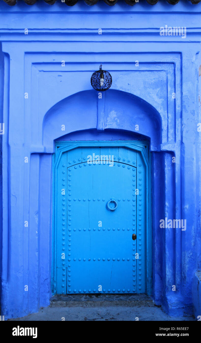 Traditionelle Pulver blau bemalte Hausfassade und verzierte Holztür in der historischen Medina von Tanger, Marokko. Stockfoto