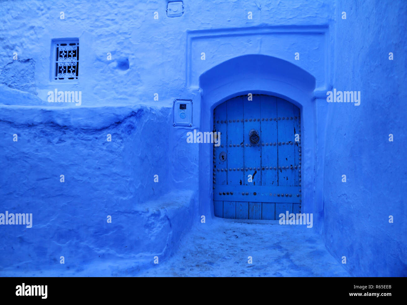Traditionelle Pulver blau bemalte Hausfassade und verzierte Holztür in der historischen Medina von Tanger, Marokko. Stockfoto
