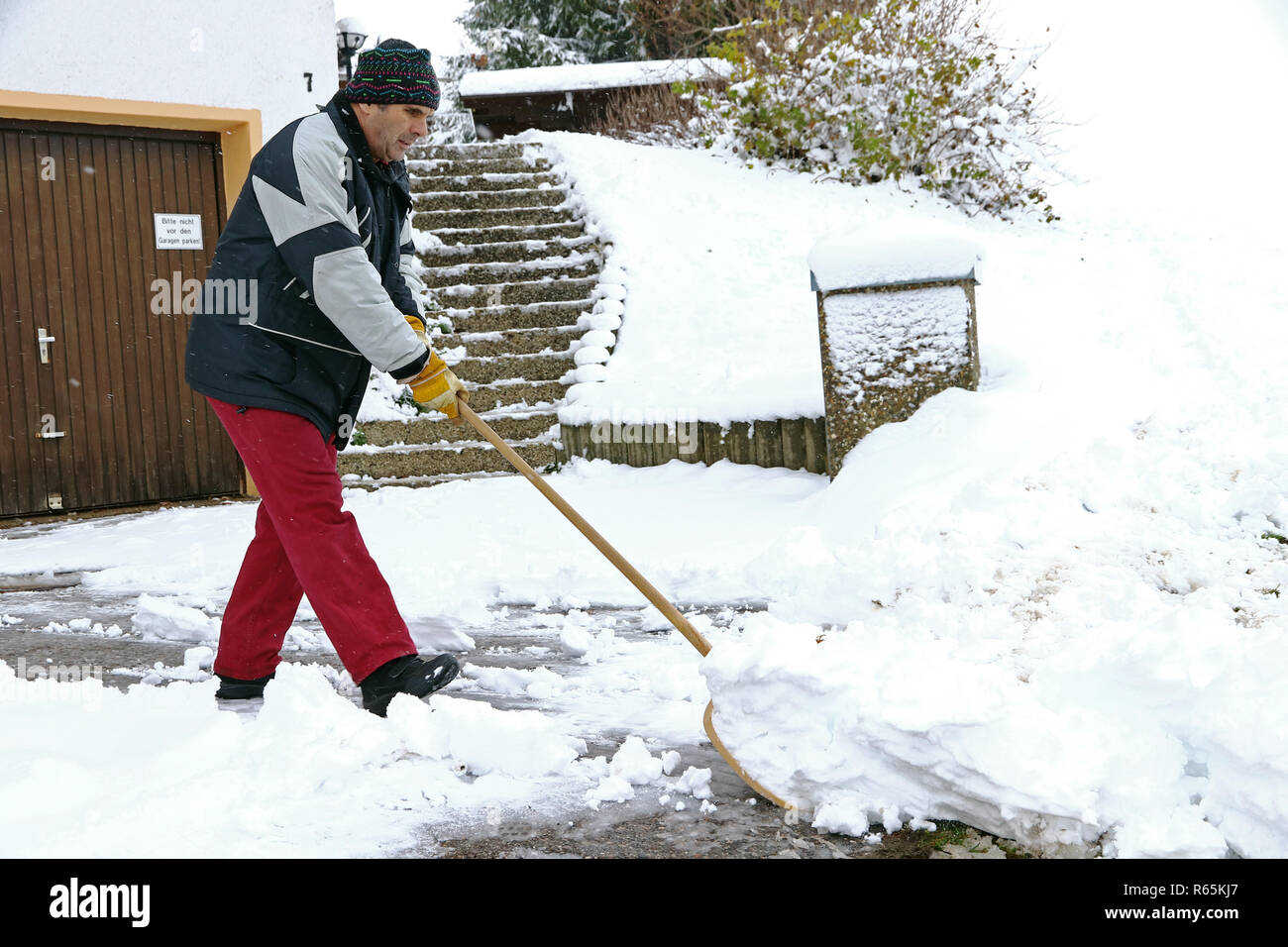 Ein Mann schaufeln Schnee vor den Garagen Stockfoto