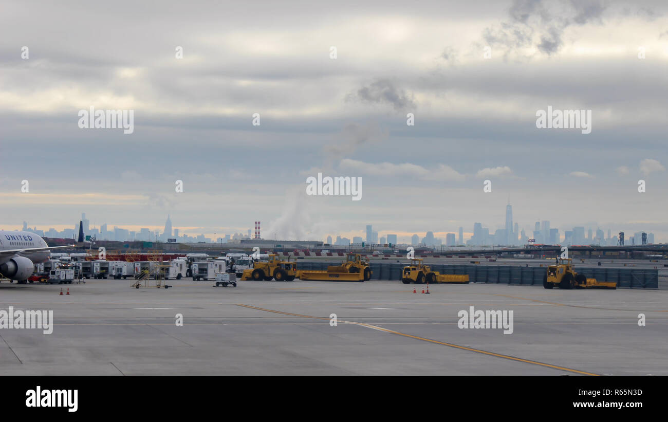 Blick auf weit entfernte Skyline von New York mit dramatischer Sonnenaufgang Himmel und Newark Liberty International Airport im Vordergrund. Stockfoto