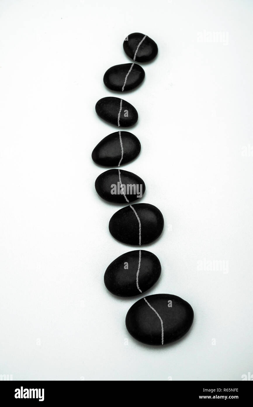 Bildung von schwarzen Steinen in Nachahmung der Wirbelsäule, in weißem Hintergrund, konzeptionelle Bild Stockfoto
