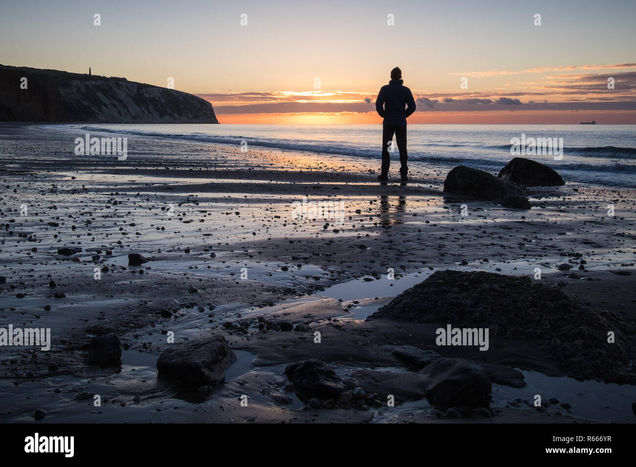Ein Mann sieht den Sonnenaufgang über die Sandown Bay auf der Isle of Wight Stockfoto