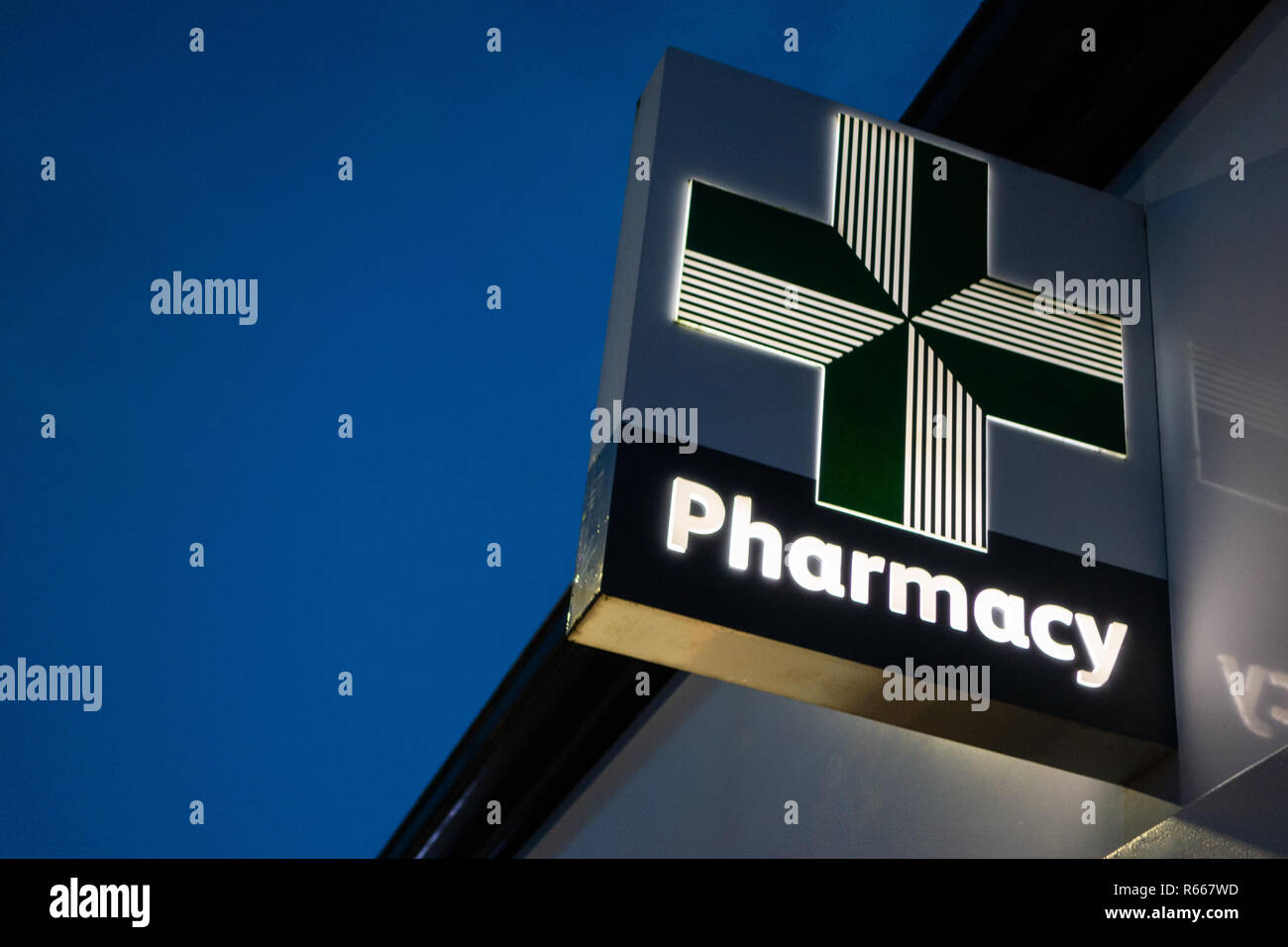 Nahaufnahme eines beleuchtete grüne Medizin Apotheke Kreuz bei Lloyds Chemiker unterzeichnen in der Dämmerung im Dinnington, Rotherham, Großbritannien Stockfoto