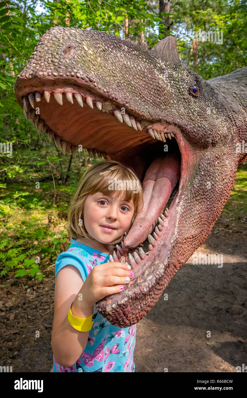 Kleine Mädchen Kopf in den Mund eines Dinosauriers Stockfoto