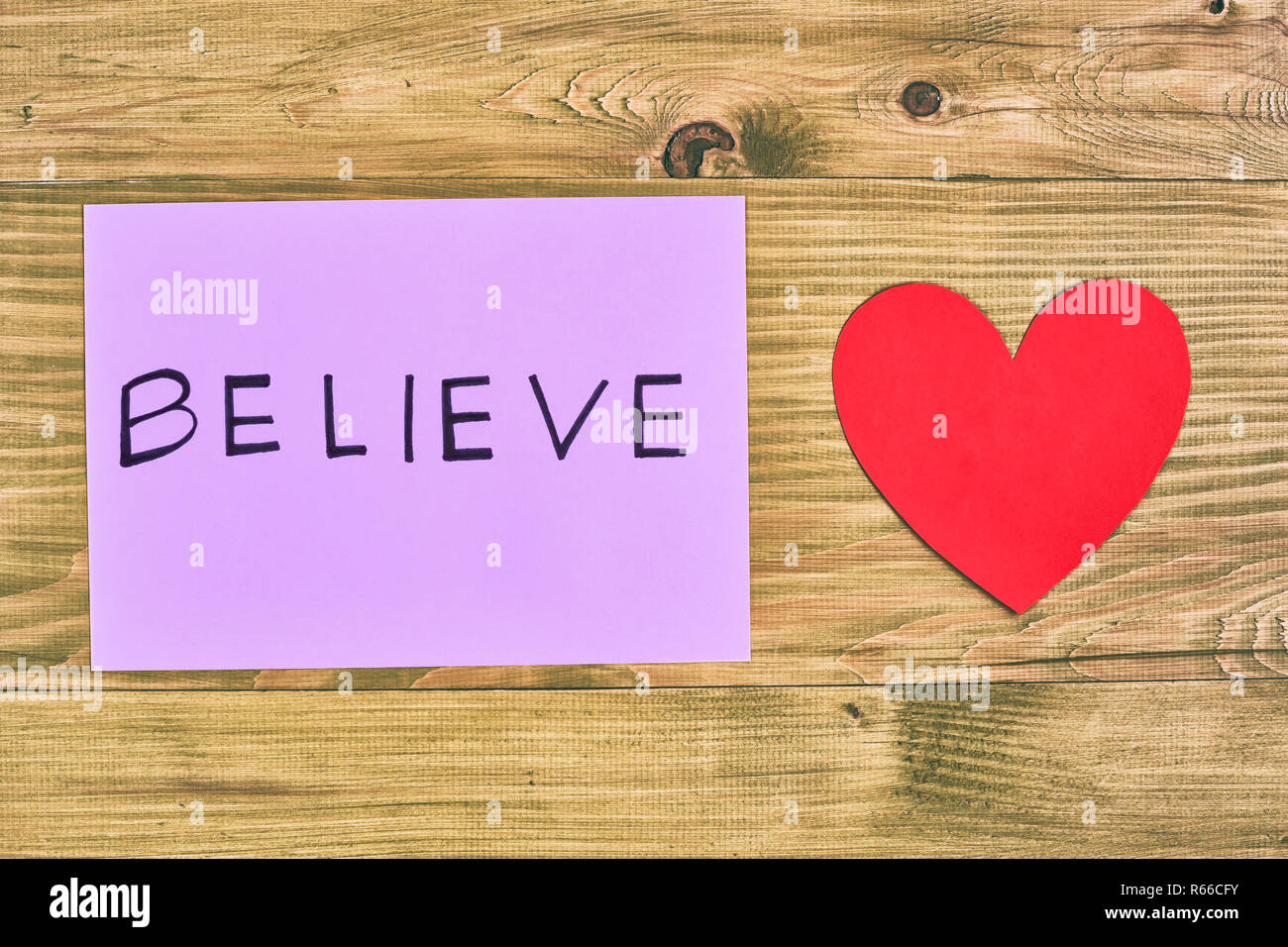 Papier mit Wort glauben und Herz Form auf Holztisch, Glaube an die Liebe. Stockfoto