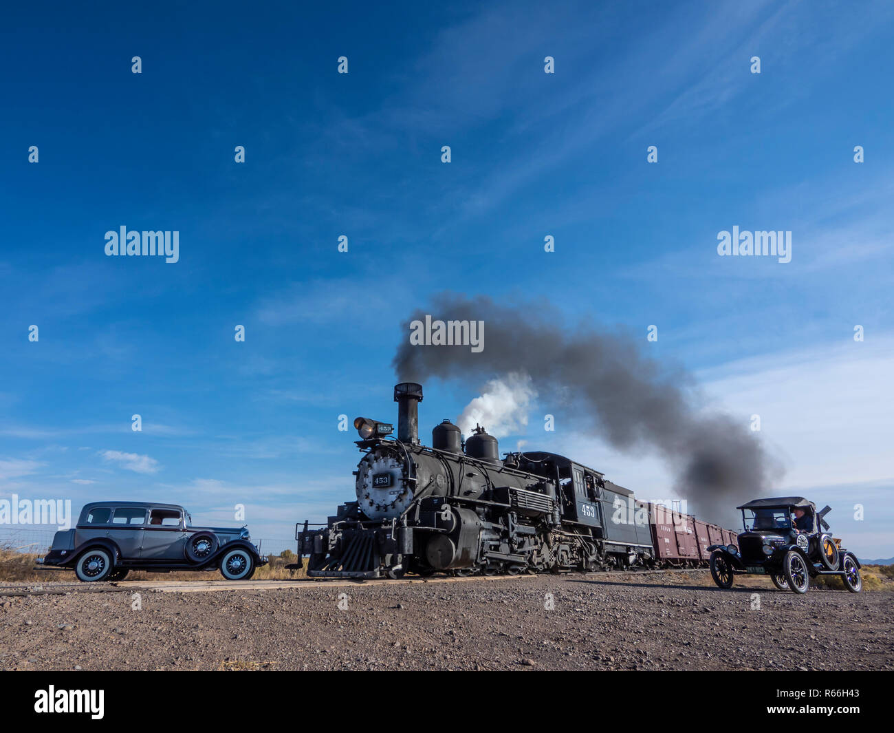 Lok 453 Dampfmaschine Güterzug Ansätze County Road E5 Kreuzung mit einem Modell - T und a 1933 Dodge durch den Titel warten. Stockfoto