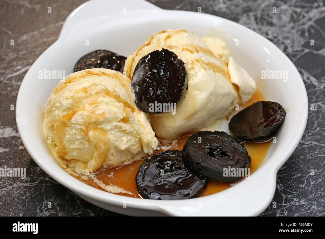 Vanilleeis mit schwarzen Nüssen in Sirup Stockfoto