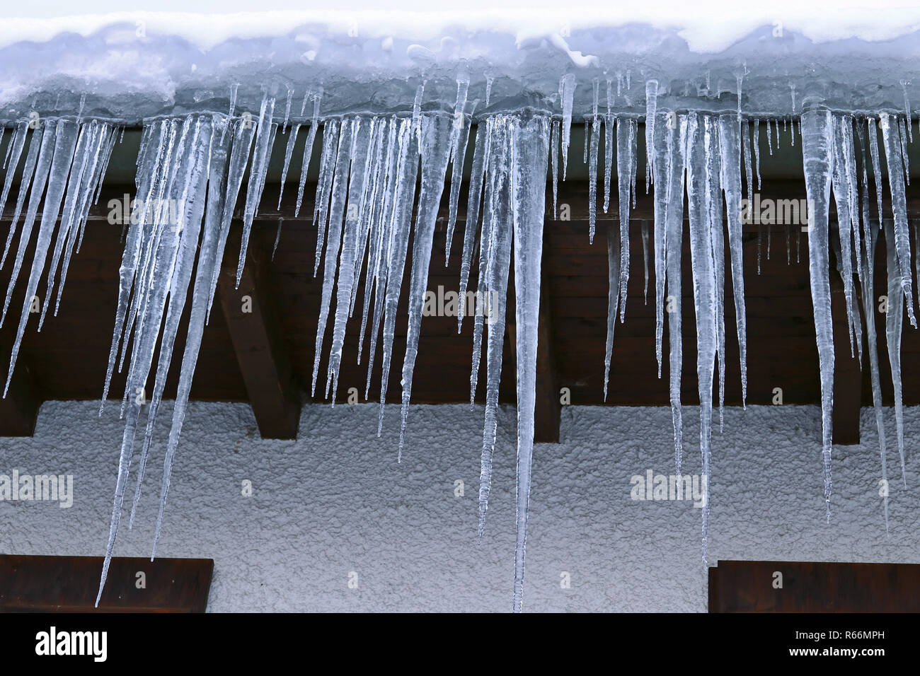 Große gefährliche Eiszapfen an einem Haus Dach im Winter Stockfoto