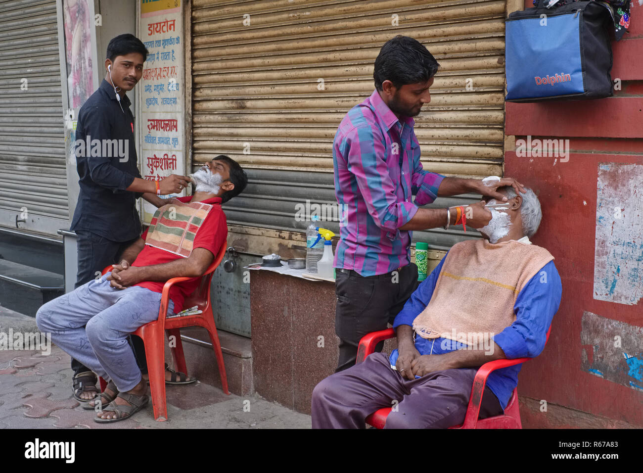 Zwei Friseure eines Open-air alon' in Kalbadevi Business Area in Mumbai, Indien, Rasieren ihren jeweiligen Kunden Stockfoto