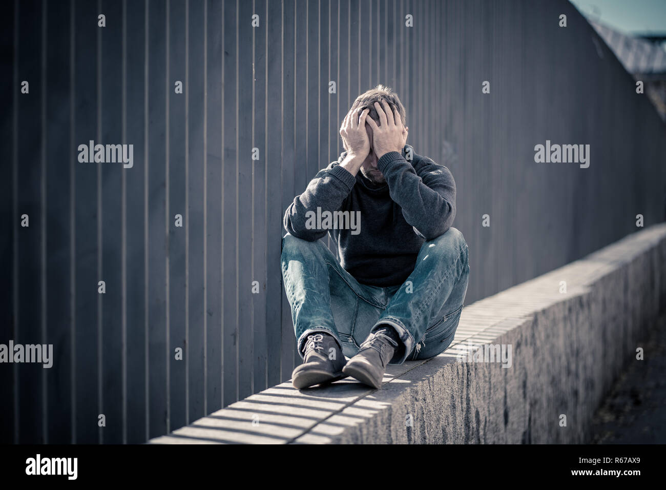 Jungen attraktiven Mann mit Depression stress sitzen allein und traurig auf der Straße Angstgefühle und einsam in Arbeitslosigkeit psychische Gesundheit Dru Stockfoto