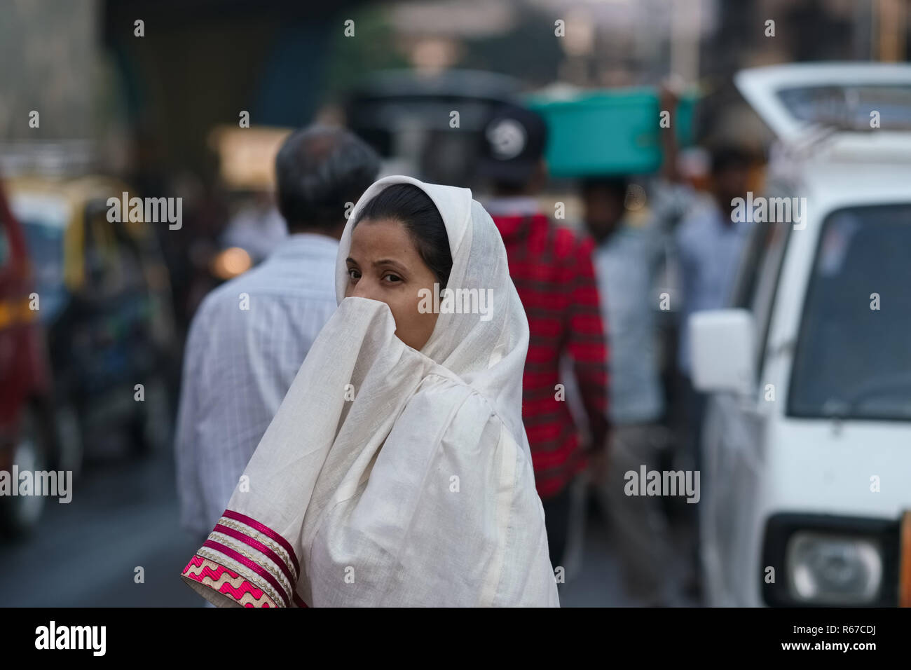 Eine junge muslimische Frau in Mumbai, Indien, b3 Sehnsucht der Bohra Gemeinschaft, teilweise verbirgt ihr Gesicht, während eine vielbefahrene Straße überqueren Stockfoto